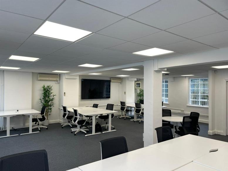 Spacious open-plan office at 37 Lombard Street with modern white desks and a large wall-mounted screen.