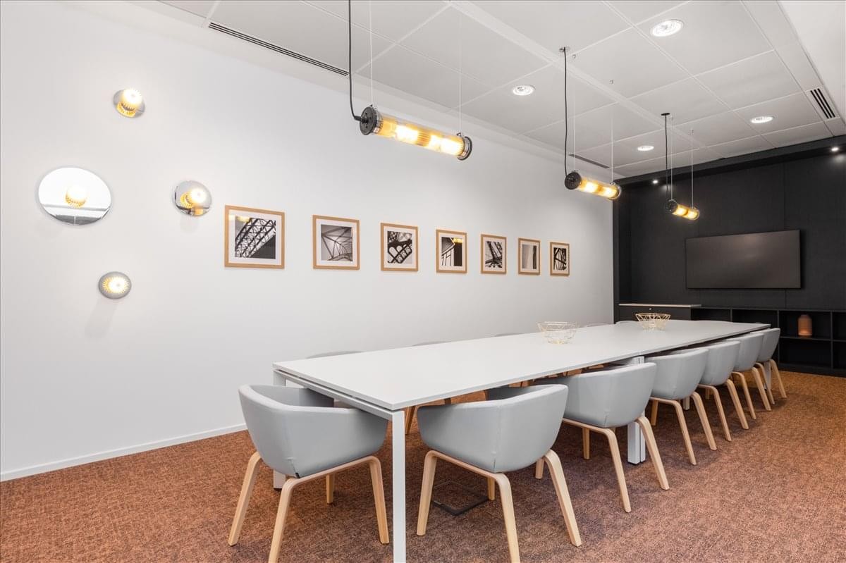 Meeting room at The Embassy featuring a long white table, grey chairs, and creative wall art.