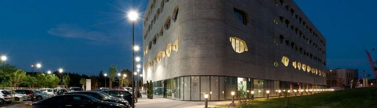 Exterior view of the modern curved building at 418 Rue du Mas de Verchant at dusk.