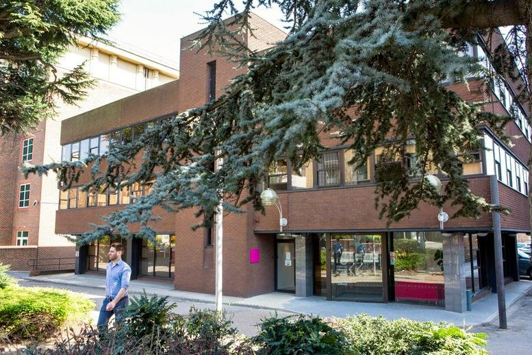 Exterior brick facade of the 42-44 Clarendon Road building behind leafy green trees.