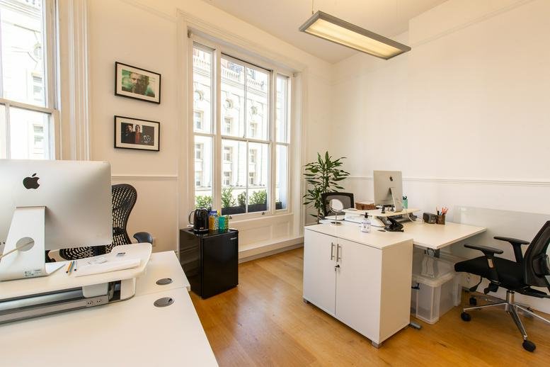 Bright office with two white desks, large sash windows, and wooden floors.
