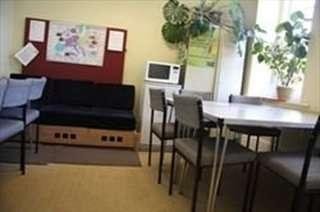 Communal break area with a sofa, dining table, microwave, and potted plants.