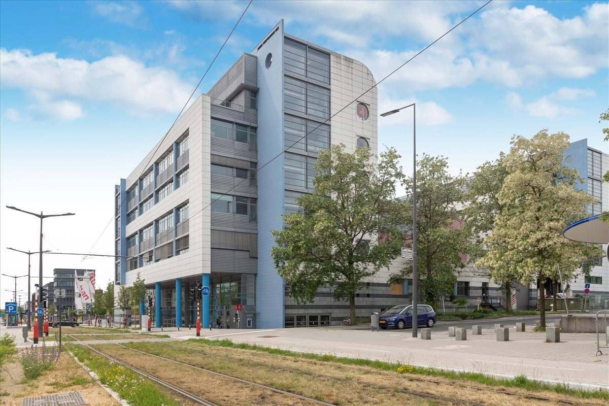 Street-side view of the modern office building facade under a blue sky.