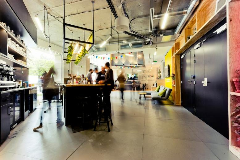 Spacious communal cafe area at 43 Rue Camille Desmoulins with a central bar and industrial ceiling.