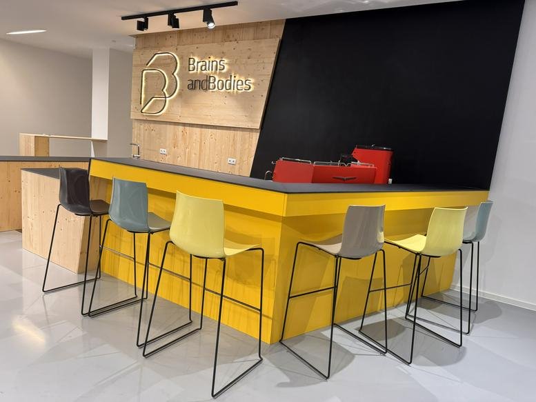 Bright reception at Brains and Bodies Coworking, Webgasse 43, Mariahilf, Vienna featuring a vibrant yellow desk.