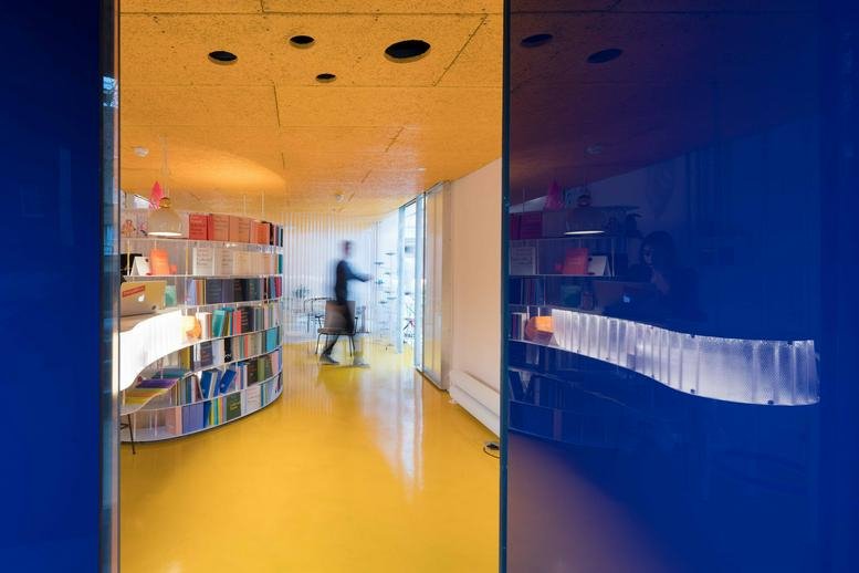 Curved library bookshelves and vibrant yellow flooring at 47–49 Princes Place.