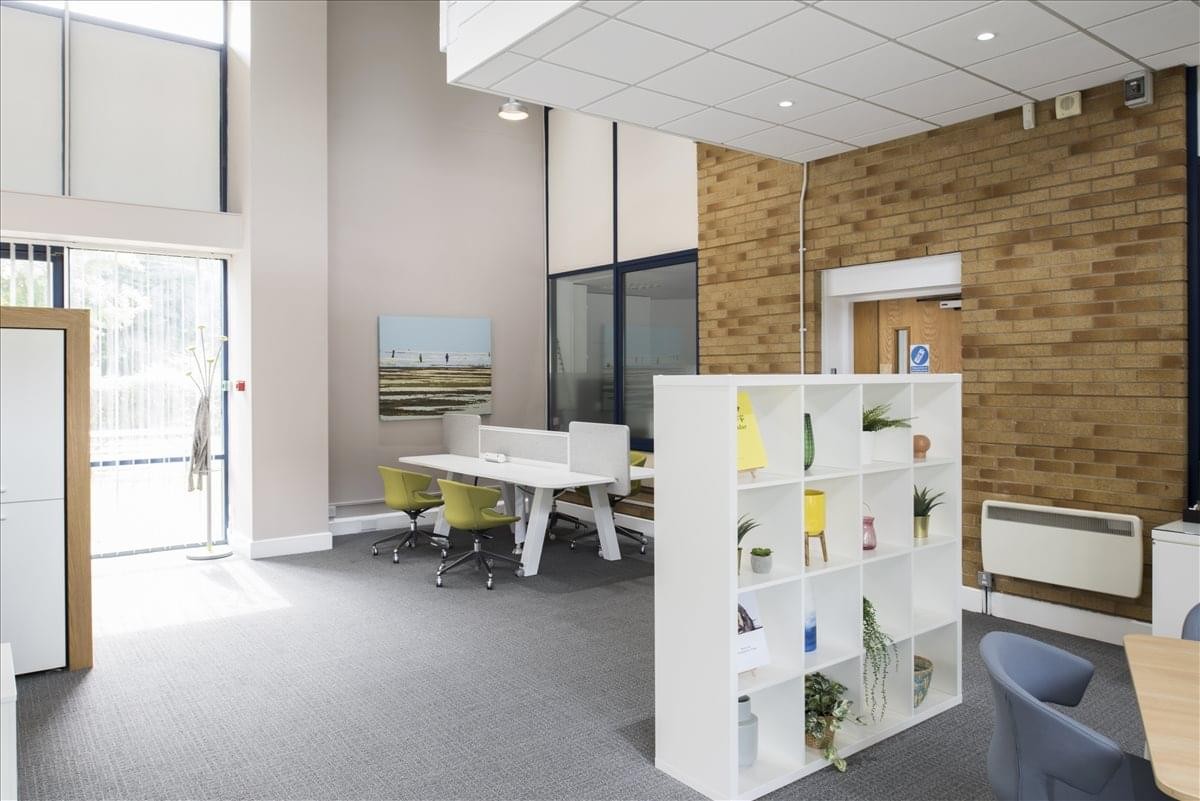 Spacious co-working area at 5 Albert Edward House featuring a white shelving unit and brick accent wall.