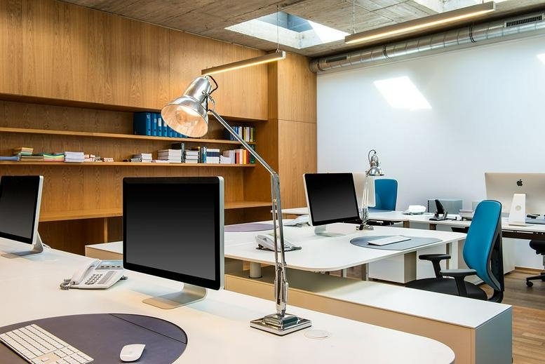 Modern open-plan workspace at 5 Rue Goethe featuring white desks, task lamps, and blue chairs.
