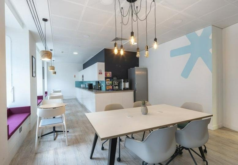 Modern communal kitchen and dining area featuring a blue feature wall and industrial pendant lighting.