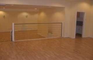 Mezzanine level communal space with light wood flooring and a minimalist metal railing.