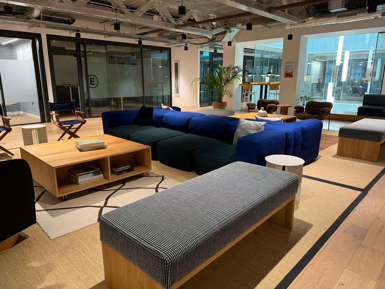 Spacious lounge area at 55 Colmore Row with a large blue velvet sectional sofa and wooden coffee table.