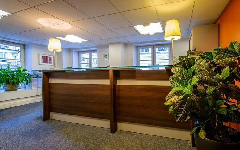 Wood-paneled reception desk at 59, rue des Petits Champs, Paris, Paris Ile de France with vibrant green plants.