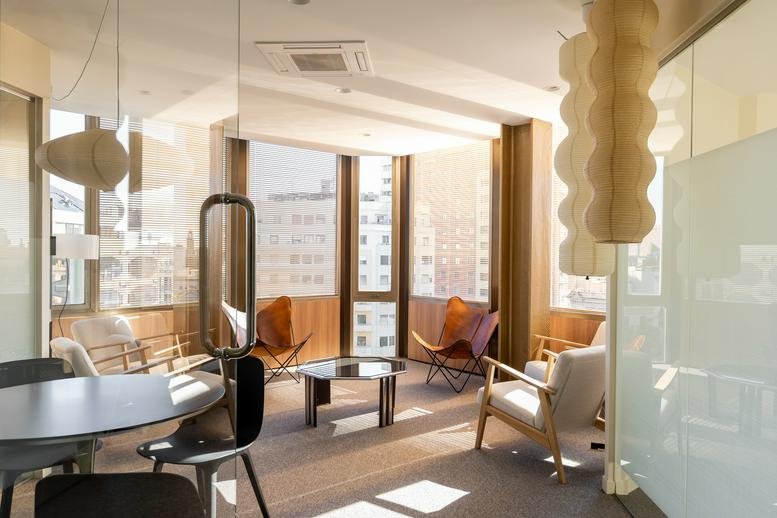 Spacious sunlit lounge at Torre Urquinaona with designer chairs and city views.