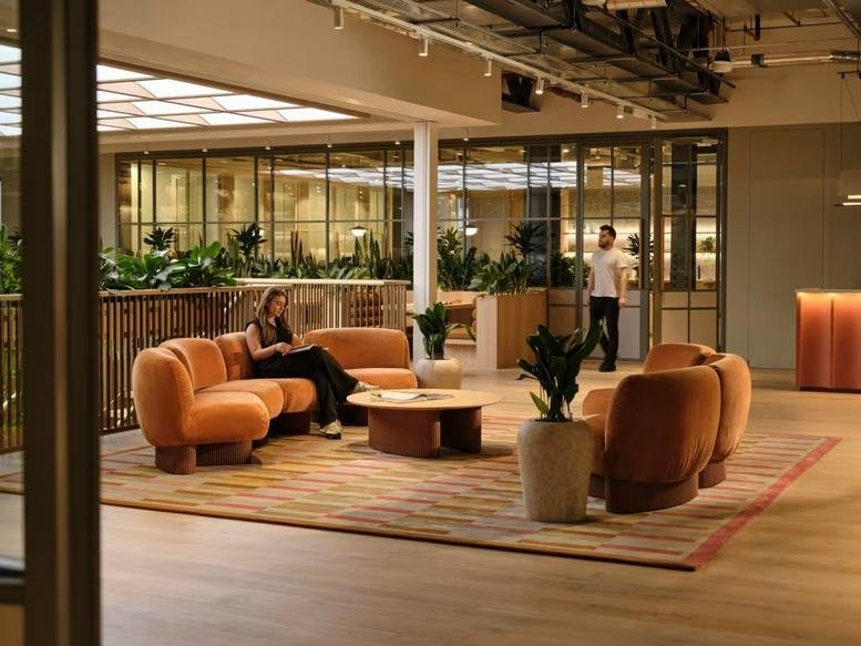 Spacious communal lounge at 60 London Wall with warm orange modular sofas and a large skylight.