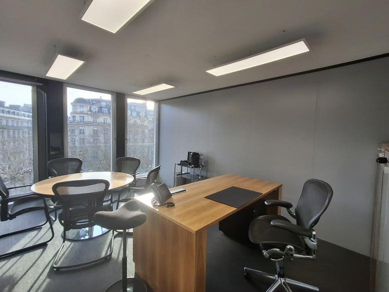 Bright private office at 66, Avenue des Champs-Élysées with a large wooden desk and meeting table.
