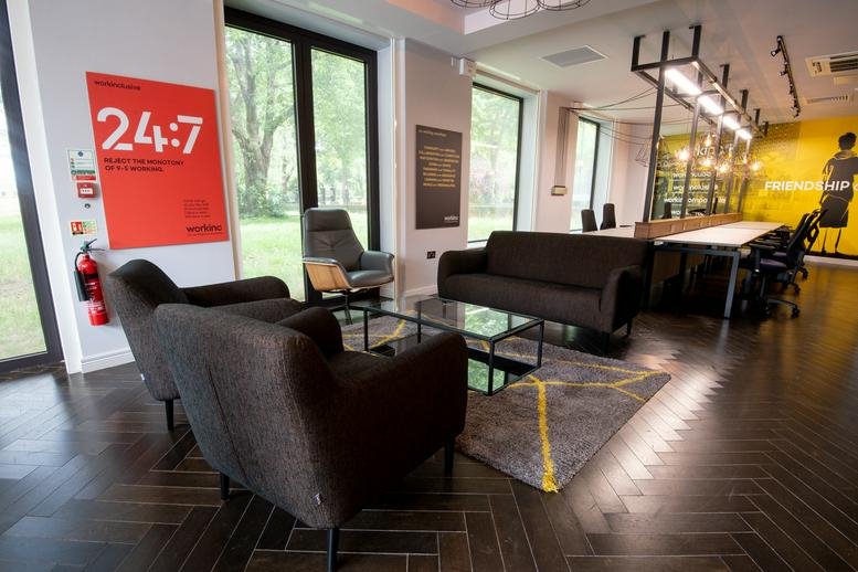 Spacious lounge at 66, West Ham Lane, London with dark armchairs and large windows overlooking greenery.