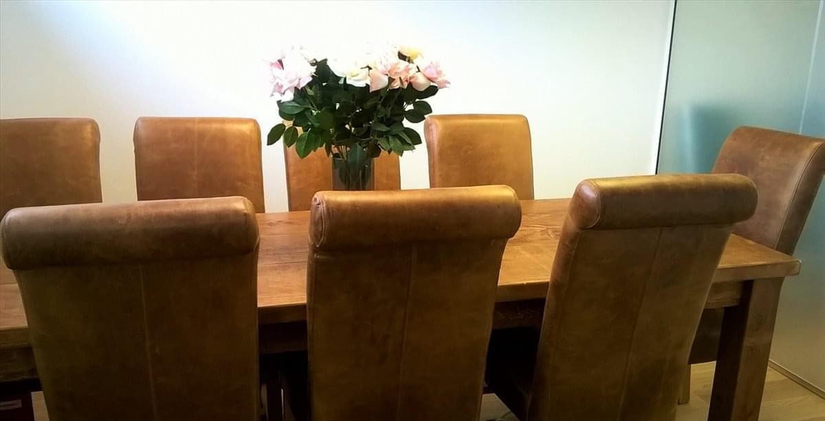 Meeting room at 67 Wingate Square with a wooden table, leather chairs, and a flower centerpiece.