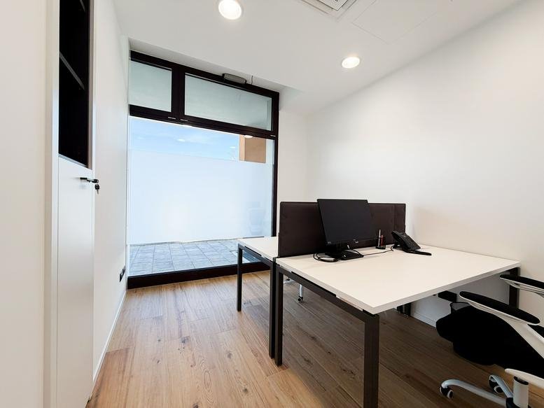 Modern private office at GRG HUB Srl with a white desk and large glass doors leading to a terrace.