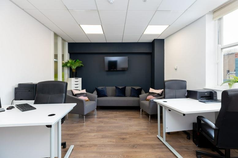Spacious open-plan office at 77 Camden Street Lower with white desks, dark grey sofa, and wooden flooring.