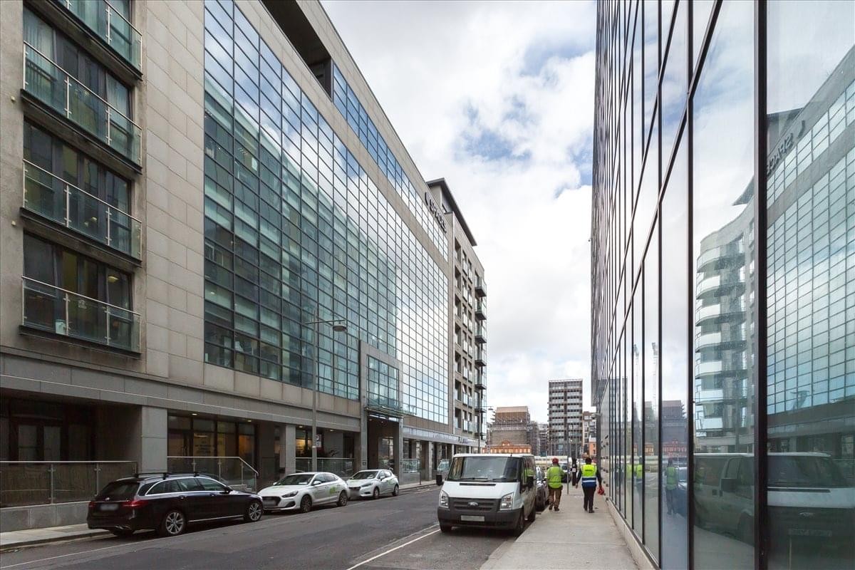 Modern glass-fronted exterior of 77 Sir John Rogerson's Quay alongside a city street.
