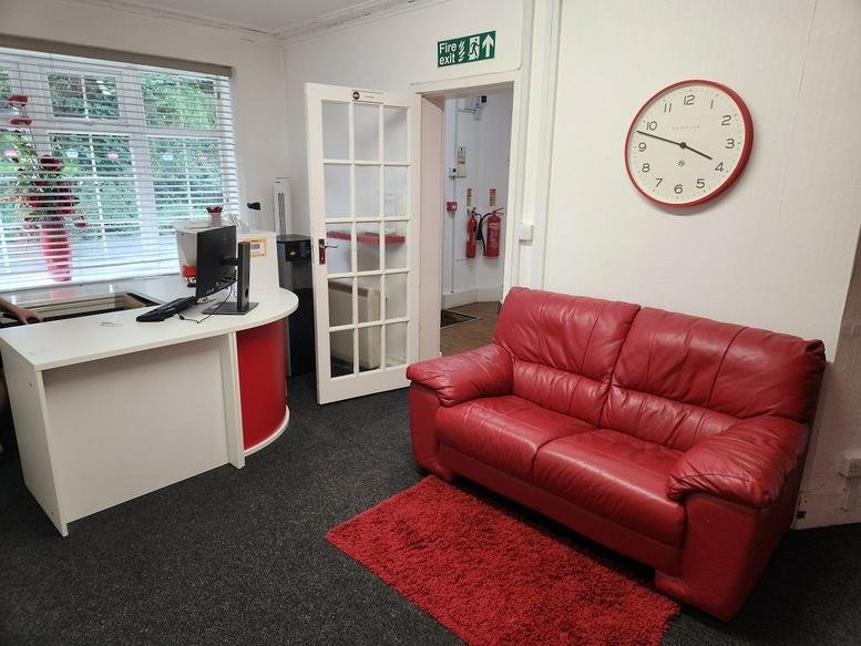 Reception area at 8 Crossways, Silwood Road with a white desk and a bright red leather sofa.