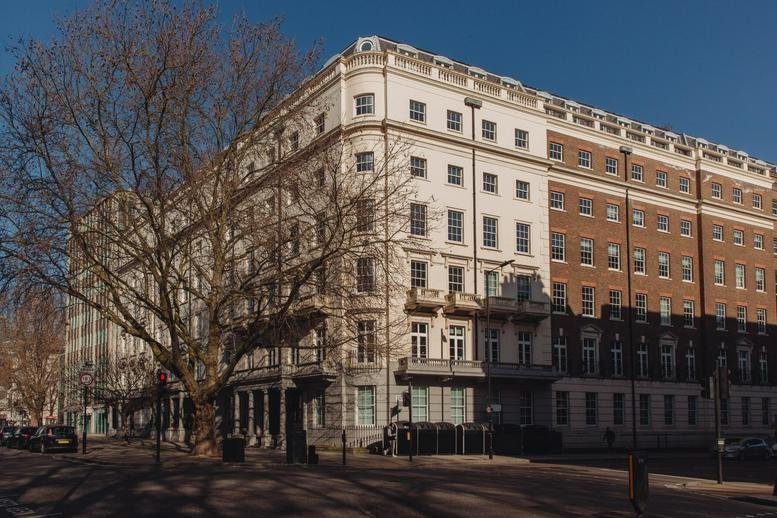 Classic white facade exterior of 84 Eccleston Square with grand balconies and a large tree in front.