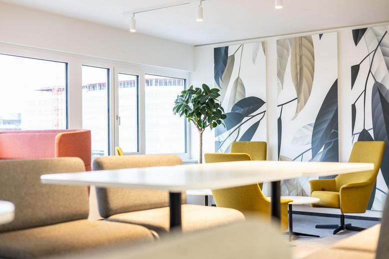 Spacious communal lounge at TwentyOne Innovation Hub with colorful chairs and botanical wall art.