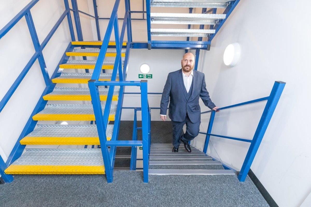 A man in a suit walks down a bright stairwell at 92 Oldfields Road, Oldfields Trading Estate.