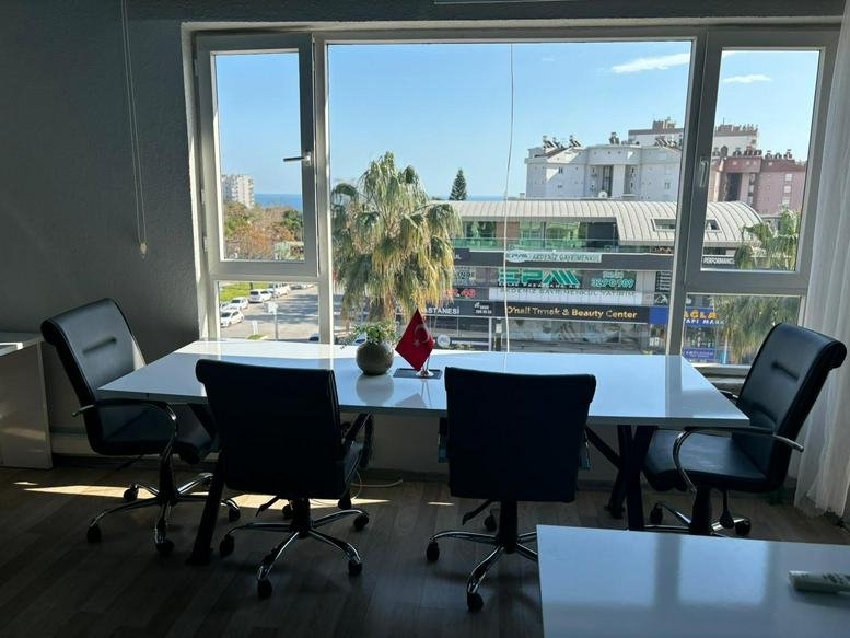 Bright meeting room at Turan Ofis Lara with a long white table and city views through large windows.