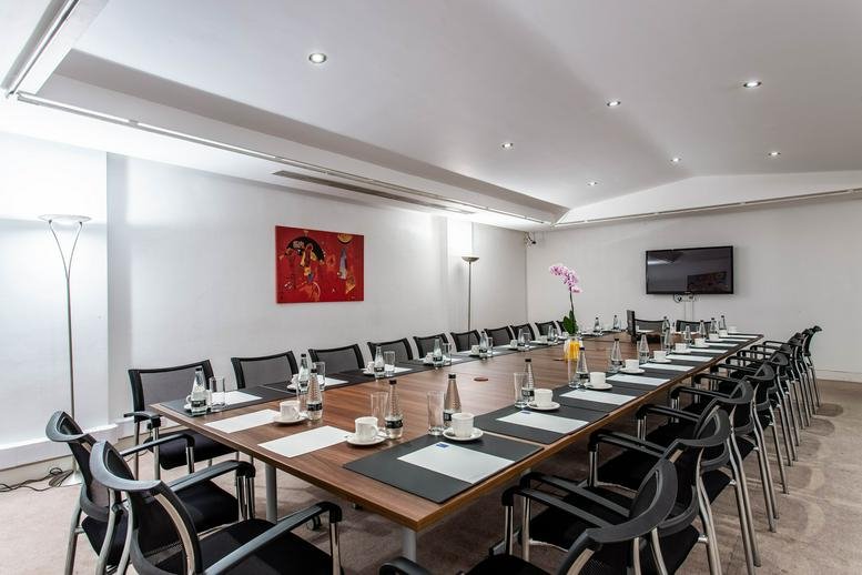 Large conference room with a long table, ergonomic chairs, and modern recessed lighting.