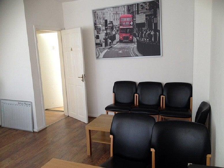Reception waiting area at Albion House with black leather chairs and a London-themed wall art.