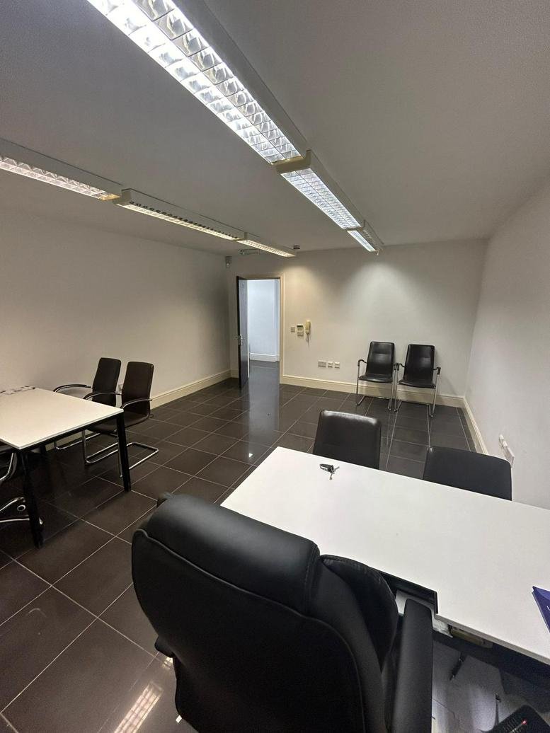 Spacious professional meeting room at Blue Ray House with modern white tables and black leather chairs.