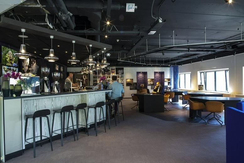 Spacious communal lounge and cafe at Amsterdam Amstel Station, Prins Bernhardplein 200 with modern bar and barstools.