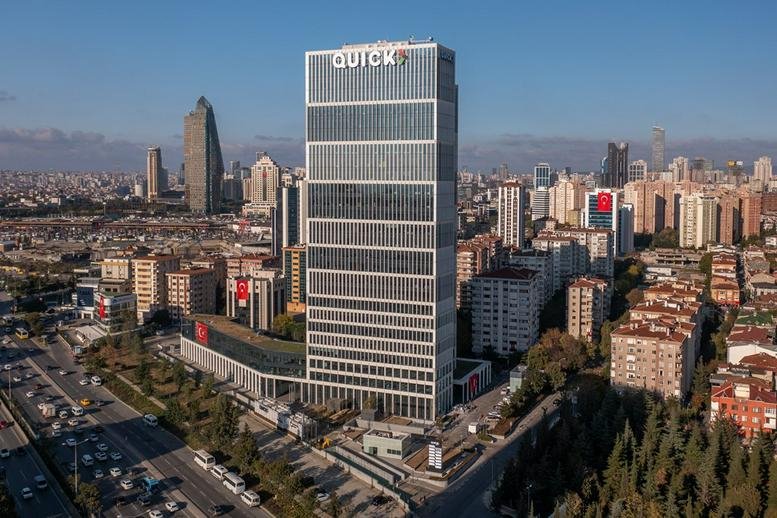 Exterior view of the glass-facade AND Kozyataği building against a blue sky.