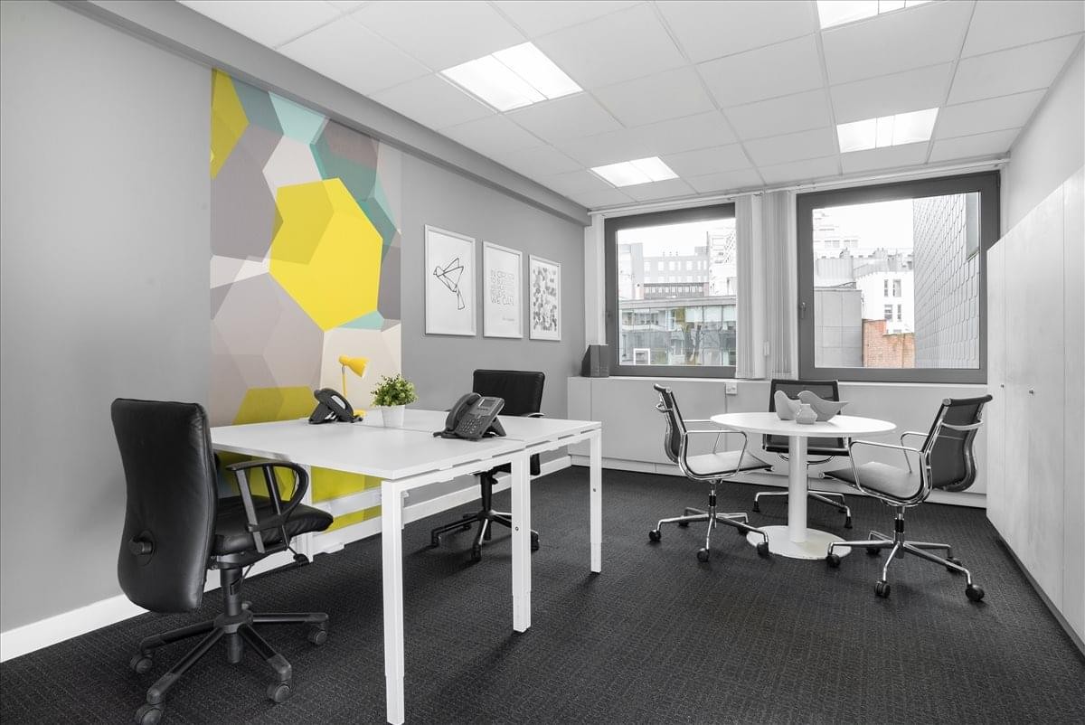 Bright office at Antwerp City Centre with a colorful geometric feature wall and several workstations.
