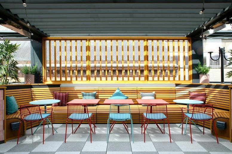 Sunny rooftop terrace with colourful chairs and booth seating at Arthur House, Arthur Street.