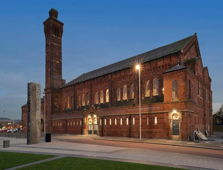 Exterior view of the historic red brick Ashton Old Baths, Stamford Street West building at dusk.