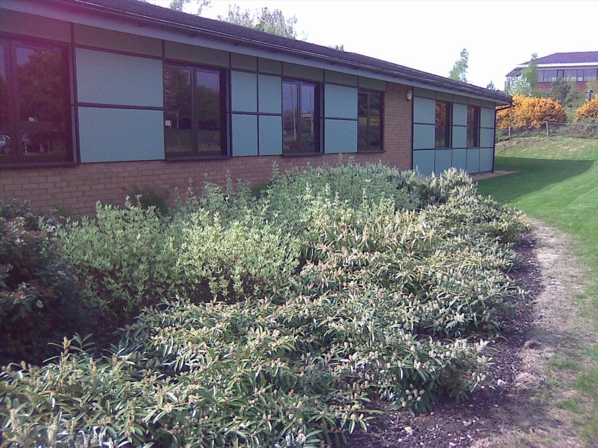 Exterior view of the brick facade and landscaped garden at Asset House, 26-28 Thorpe Wood Business Park.