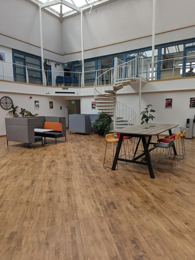 Spacious communal atrium at Atrium Business Centre featuring a spiral staircase, skylights, and wooden flooring.