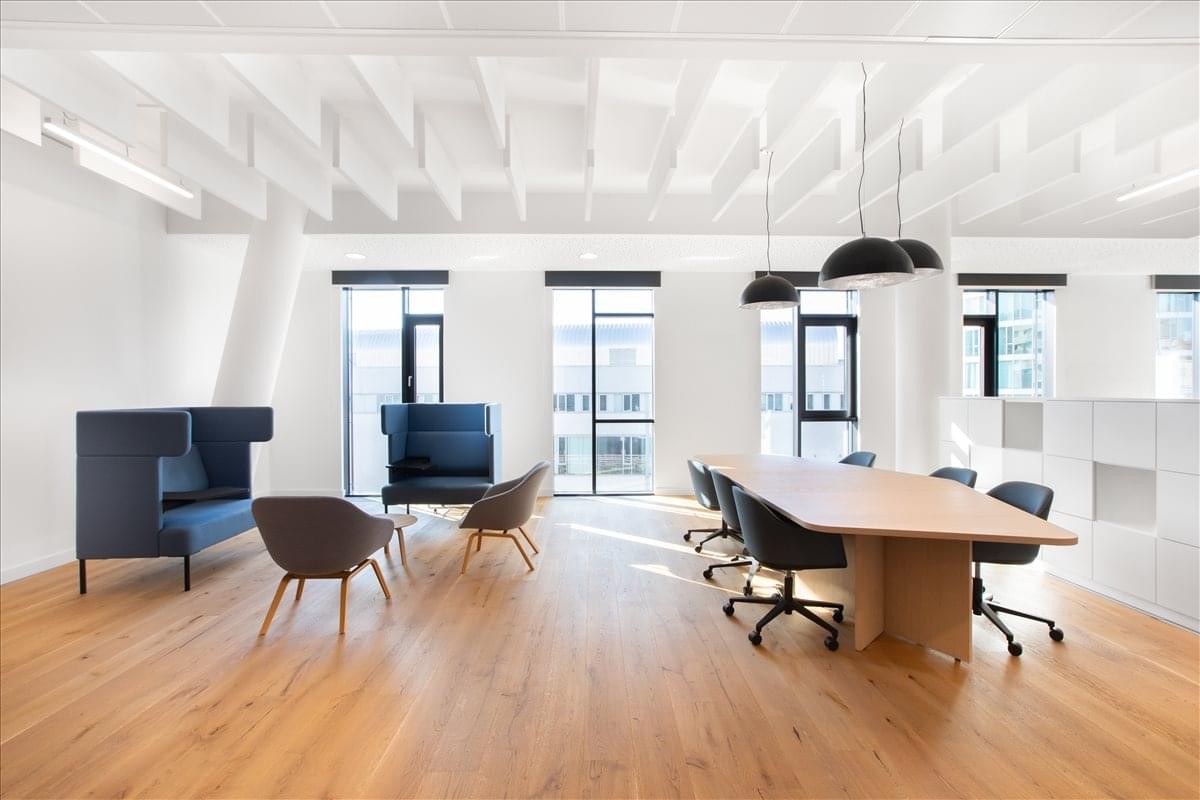 Spacious wooden-floored communal lounge with blue high-back sofas and meeting table at Ausstellungsstraße 50.