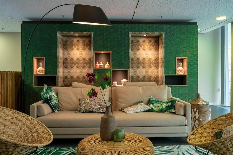 Spacious lounge area at Baseler Strabe 10 with a green feature wall and stylish wicker chairs.