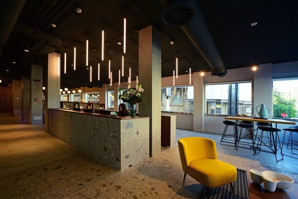 Spacious reception area at Bastioni di Porta Nuova 21 with stylish yellow armchair and vertical lighting.