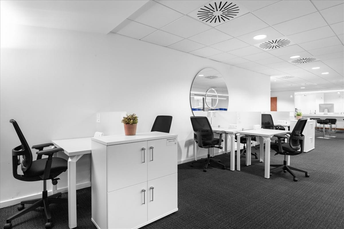 Open-plan workspace at Beaconsfield MSA, Windsor Drive, Regus Express featuring white desks and black ergonomic chairs.
