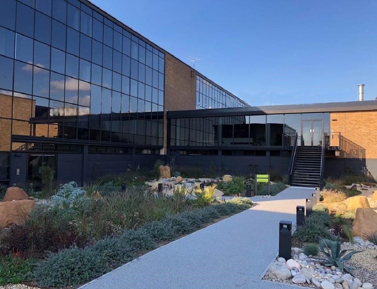 Modern exterior of the glass-fronted Bedford Heights building with a landscaped garden path.