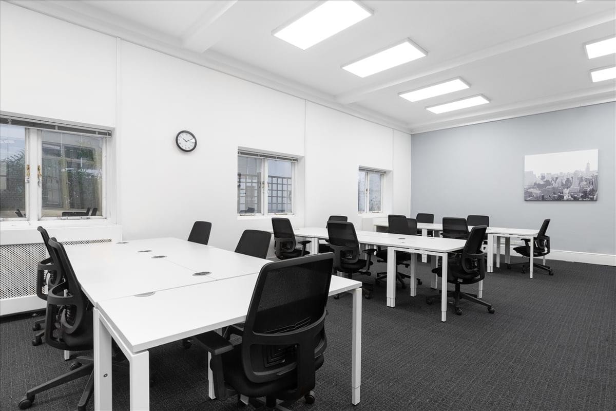 Spacious open-plan workspace at Bloomsbury House with rows of white desks and black ergonomic chairs.