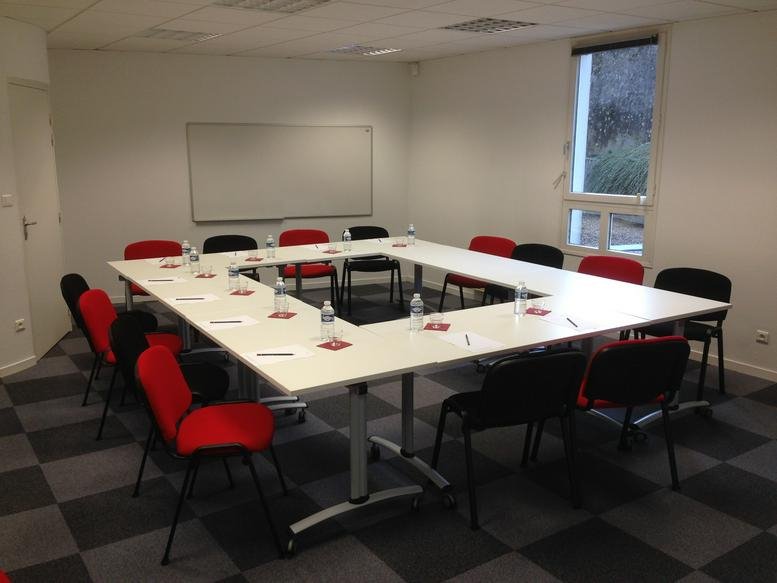 Professional meeting room at Bordeaux Quinconces, 9 rue de Condé with U-shaped table and red accent chairs.