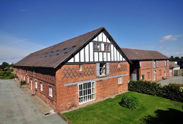 Exterior view of the historic brick and timber-framed Bretton Hall with a manicured lawn.