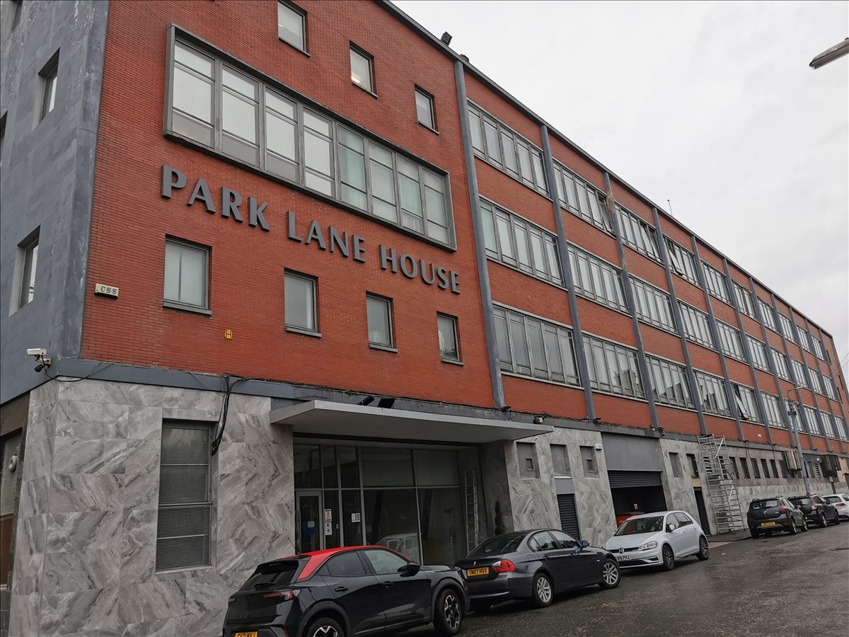 Exterior red brick facade of Broad Street Business Complex with large windows and street parking.