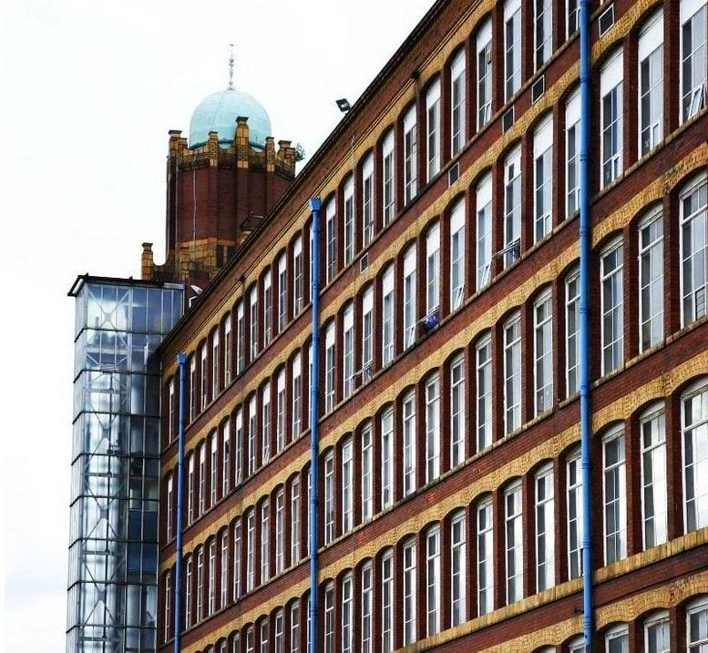 Exterior view of the historic red brick facade and domed tower of Broadstone Mill.