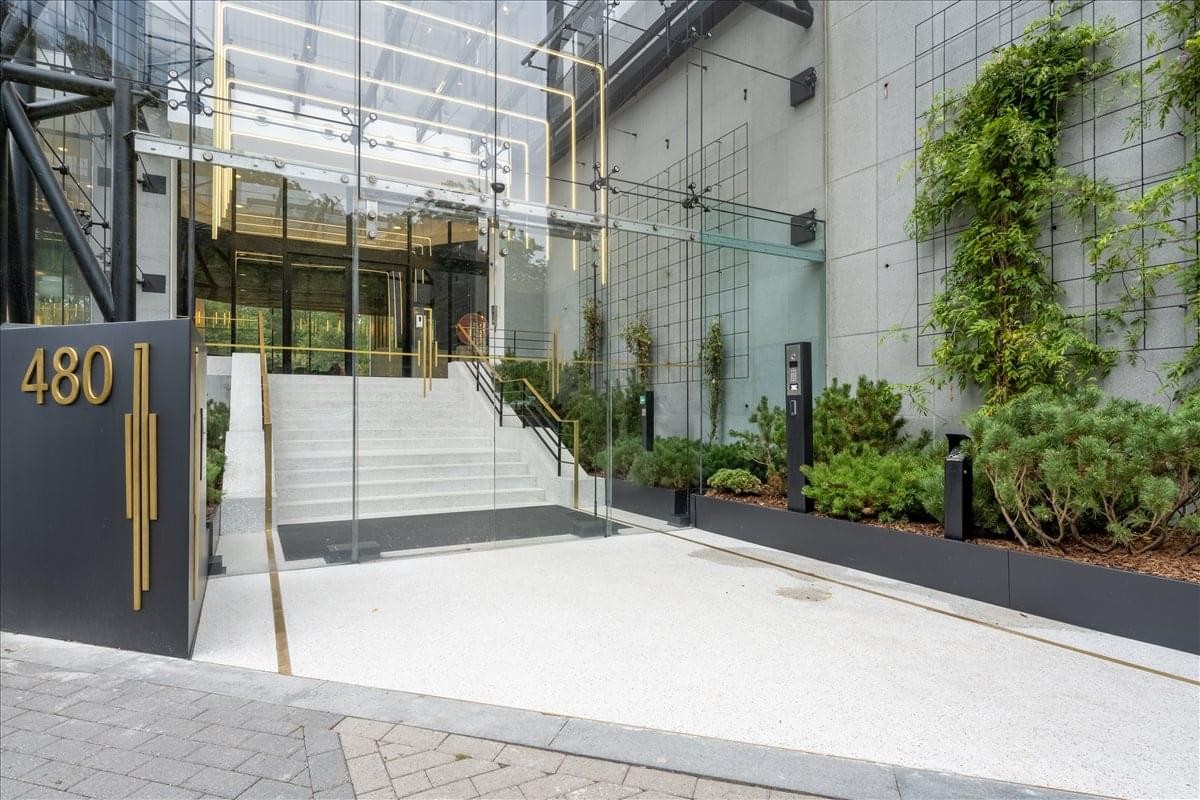 Exterior entrance of the Brussels IT Tower at Avenue Louise 480 featuring glass architecture and greenery.
